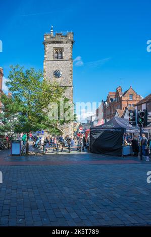 La gente fuori e circa il giorno di mercato di sabato, alcuni che prendono una pausa ha seduto sotto la torre dell'orologio. St Albans, Hertfordshire, Inghilterra, Regno Unito Foto Stock