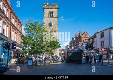 La gente fuori e circa il giorno di mercato di sabato, alcuni che prendono una pausa ha seduto sotto la torre dell'orologio. St Albans, Hertfordshire, Inghilterra, Regno Unito Foto Stock