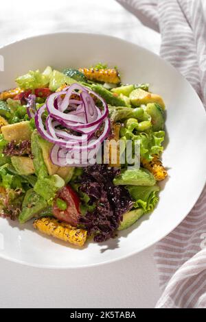 Insalata di cibo sano con verdure di edamame e avocado, fagioli di edamame, peperoni, mais, cetrioli, pomodori, cipolle rosse su fondo bianco per la res Foto Stock