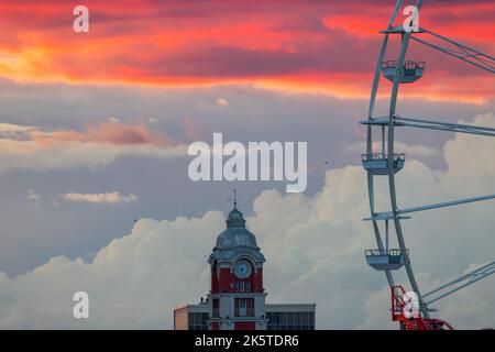Vecchia torre orologio della stazione ferroviaria di Varna città, Bulgaria e uccelli volanti al tramonto Foto Stock