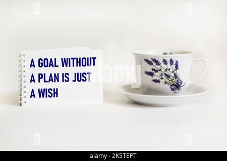 Un obiettivo senza un piano è solo un desiderio - testo su un blocco note con una penna e una tazza di caffè su uno sfondo bianco Foto Stock