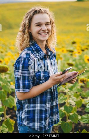 Donna contadina che usa un tablet intelligente nel giardino di girasole. Concetto : contadino intelligente. Utilizzo di dispositivi wireless tecnologici per lo studio o la ricerca sull'agricoltura. Foto Stock