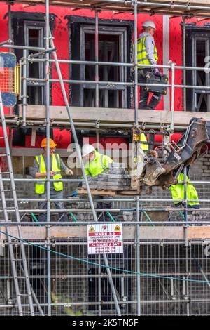 Preston Dryliners, muratori stanno installando Woodward Lewis Antique facing Brick. Rivestimento in pietra coursed Weather-ored rustici blocchi grigi, per coprire Proctor Wraptite una soluzione unica esterna ermetica, che è permeabile al vapore, ma ermetica; membrana e isolamento sul cantiere. Morar New Build Care Home, semplicemente Regno Unito. Costruzione di vie di navigazione a Preston, Regno Unito Foto Stock