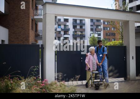 Caregiver che cammina con il cliente anziano di fronte a casa di cura. Foto Stock