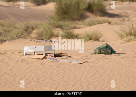 Metallo, plastica e altri rifiuti e rifiuti lasciati da esseri umani inquinando l'ambiente desertico a Dubai, Emirati Arabi Uniti. Foto Stock