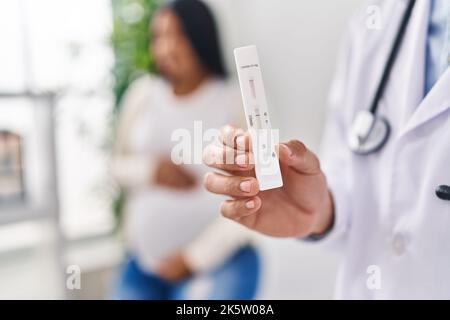 Giovane medico di coppia latino e paziente che ha consultazione medica che tiene il test antigene in clinica Foto Stock