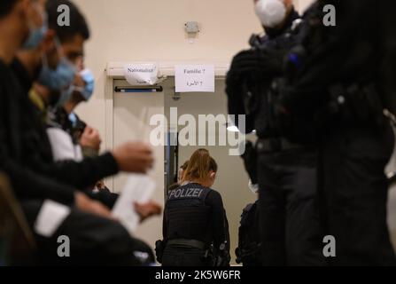 Dresda, Germania. 10th Ott 2022. I rifugiati provenienti dalla Siria attendono la registrazione nella zona di arrivo per i rifugiati alla stazione ferroviaria principale e sono accompagnati da agenti di polizia federali. Credit: Robert Michael/dpa/Alamy Live News Foto Stock