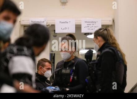 Dresda, Germania. 10th Ott 2022. I rifugiati provenienti dalla Siria attendono la registrazione nella zona di arrivo per i rifugiati alla stazione ferroviaria principale e sono accompagnati da agenti di polizia federali. Credit: Robert Michael/dpa/Alamy Live News Foto Stock