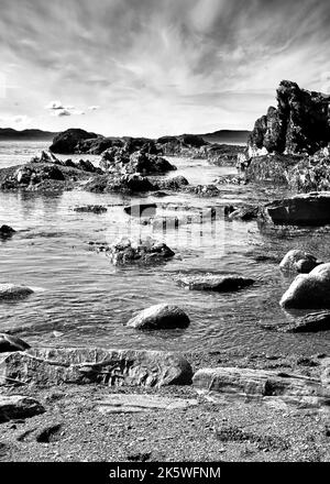 L'immagine in bianco e nero mostra le frastagliate rocce scure dell'oceano sotto un cielo spettacolare a Botanical Beach, Vancouver Island, BC Foto Stock