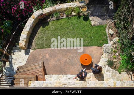 Giardino all'inglese sul retro che si affaccia sulla terrazza all'aperto al piano superiore. Kareela Crest House, Cremorne, Australia. Architetto: Bijl architettura, 2022. Foto Stock