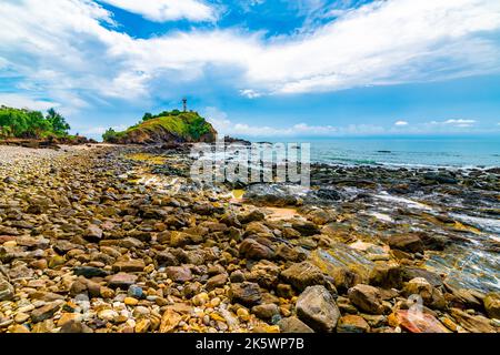 Faro sulla roccia al parco nazionale di Mu Ko Lanta, Thailandia. Vista dalla spiaggia con pietre. Estate tempo, cielo blu con nuvole. Foto Stock