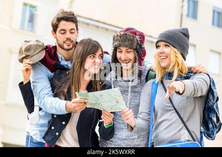 Gruppo di giovani turisti hipster amici tifosi con la mappa della città nel centro storico - concetto di stile di vita di viaggio con persone felici divertirsi insieme - Wint Foto Stock