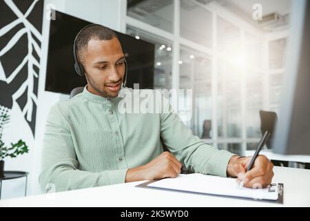 Uomo d'affari africano fiducioso prendere appunti mentre si parla al telefono con il cliente in un ufficio moderno Foto Stock