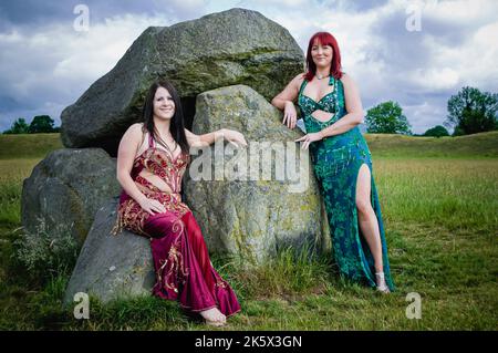 Due ballerini del ventre indossano un costume da bagno, posano al giant's Ring Stone dolmen, Belfast, Irlanda del Nord Foto Stock