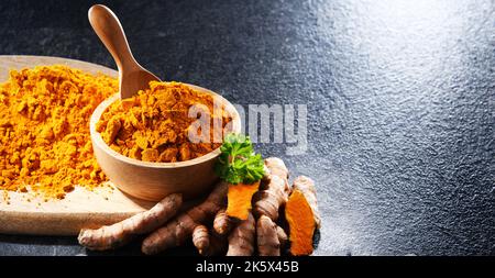 Composizione con una ciotola di curcuma macinato e il suo rizoma fresco. Foto Stock