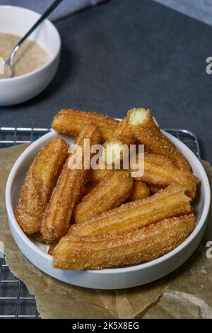 primo piano dei churros con lo zucchero nel recipiente bianco, vista dall'alto Foto Stock