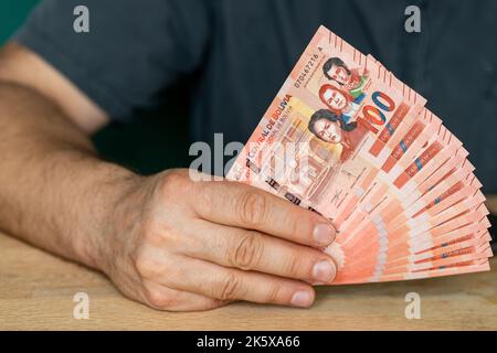 L'uomo dietro la scrivania sta tenendo un pacchetto di soldi boliviani Foto Stock