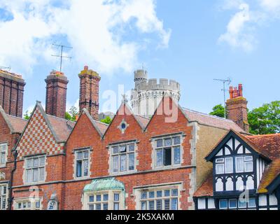 Arundel strada urbana di mattoni vecchi Uniti case a schiera con castello dietro appartamenti e negozio edificio Foto Stock
