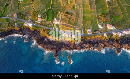 Foto con drone della costa, che mostra la campagna, alcune case e l'oceano dell'isola Graciosa, dall'alto. Foto Stock