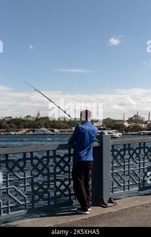 Vista dell'irriconoscibile pescatore sul ponte Galata di Istanbul. L'immagine riflette lo stile di vita e la cultura della gente locale è una giornata estiva di sole. Foto Stock