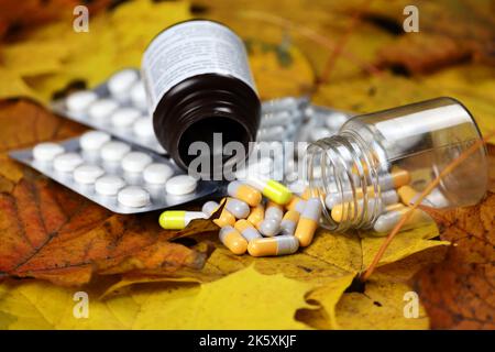 Pillole su foglie di acero giallo, flaconi di capsule e confezioni di compresse. Farmacia, antidepressivi, vitamine per l'immunità in autunno stagione influenzale Foto Stock