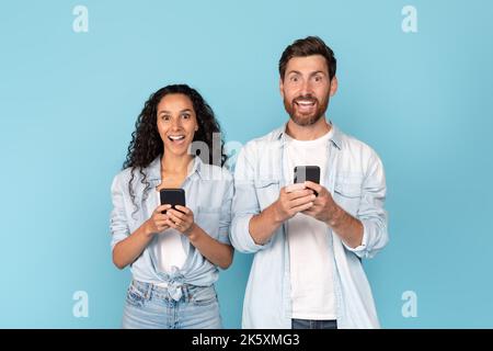 Sorpreso felice uomo caucasico millenario con barba e donna araba in chat casual in smartphone Foto Stock