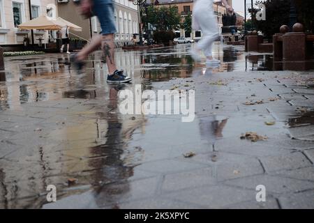Città strade dopo la pioggia pesante. A piedi nudi sui marciapiedi con pozze e riflessi Foto Stock