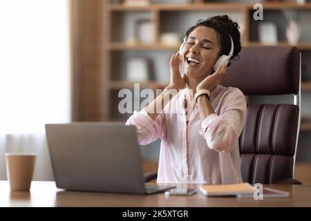 Felice giovane donna d'affari che ascolta musica e canta in ufficio Foto Stock
