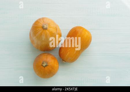 Tre zucche arancioni su sfondo verde d'annata menta. Vista dall'alto di una composizione minimalista di zucca con spazio per il testo. Luce naturale calda e Foto Stock