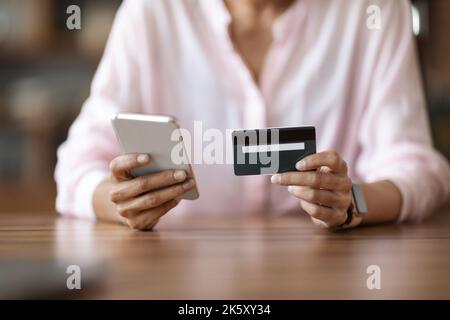 Corto di donna che tiene il telefono delle cellule e la carta di credito Foto Stock