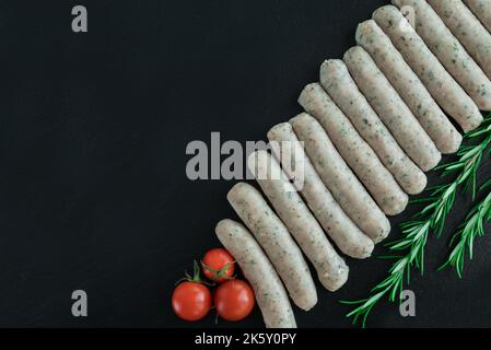 Costolette di maiale crude con pepe e rosmarino su fondo scuro Foto Stock
