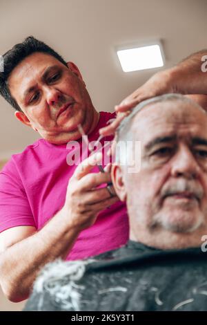 vecchio che ottiene un taglio di capelli Foto Stock