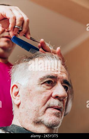 vecchio che ottiene un taglio di capelli Foto Stock