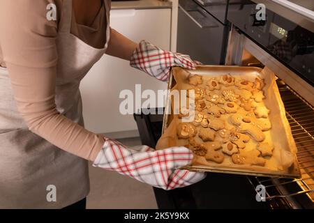 Una donna prende il pan di zenzero, biscotti di natale fuori dal forno Foto Stock