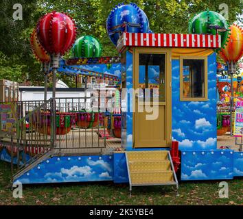 Fiera di Parsons Green, West London, Regno Unito; giostre colorate super luminose, mongolfiere, Auto, treni e Spiderman Foto Stock