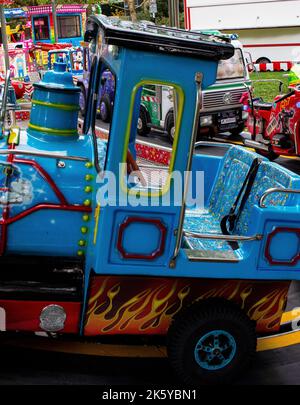 Fiera di Parsons Green, West London, Regno Unito; giostre colorate super luminose, mongolfiere, Auto, treni e Spiderman Foto Stock