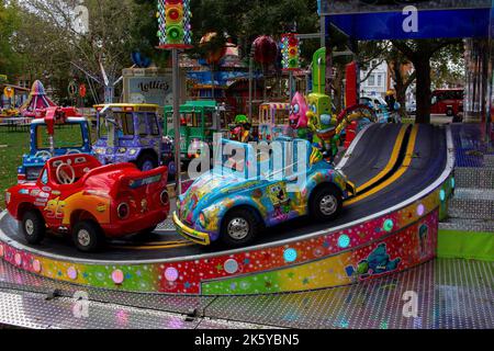 Fiera di Parsons Green, West London, Regno Unito; giostre colorate super luminose, mongolfiere, Auto, treni e Spiderman Foto Stock