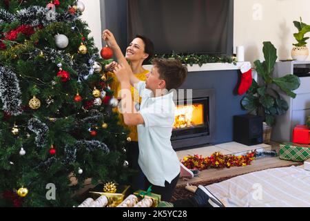 Madre e figlio caucasici che trascorrono del tempo insieme a decorare l'albero di natale Foto Stock