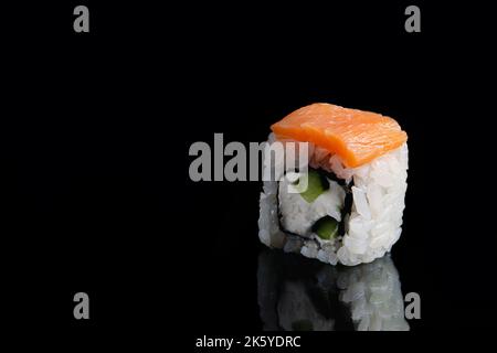 Philadelphia sushi roll su sfondo nero con riflesso. Rotoli Uramaki. Piatto asiatico popolare di riso e salmone. Consegna rapida di piatti da asporto giapponesi Foto Stock