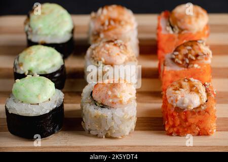 Set di sushi roll sul vassoio di bambù da portata. Primo piano per Uramaki e futomaki roll. Serve cucina Giapponese. Popolare piatto asiatico di riso e frutti di mare sul nero Foto Stock