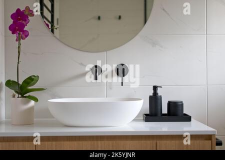 Moderno bagno bianco con rubinetti neri e accessori. Foto Stock