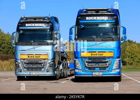 Due camion Volvo FH blu davanti ai semirimorchi per il trasporto di carichi eccezionali parcheggiati in un cortile. Paimio, Finlandia. Settembre 22, 2022. Foto Stock