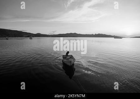 Solitaria piccola barca con bello bianco e nero, riflesso in acqua Foto Stock
