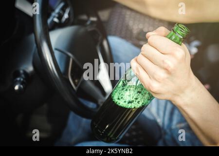 Autista alcolico con una bottiglia di birra alla guida di un'auto Foto Stock