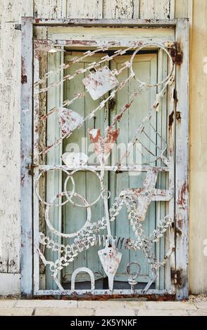 Porta in metallo fatta di figure diverse all'ingresso della casa in legno di legno grezzo Foto Stock