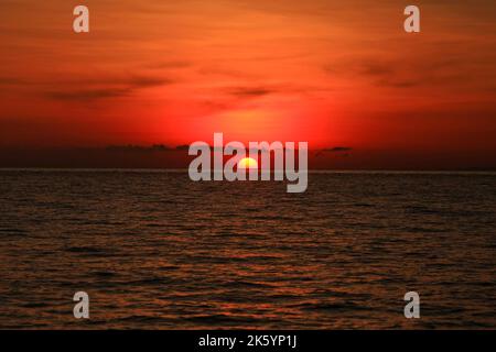 Un'immagine di un bel tramonto rosso con un grande sole giallo Foto Stock