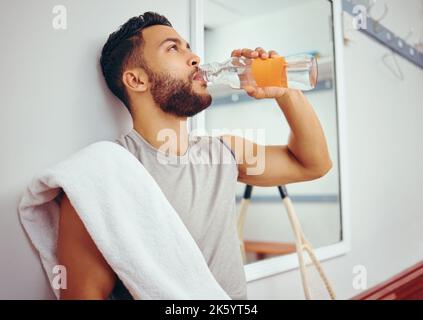 Giocatore ispanico bere acqua dopo la sua partita. Giovane giocatore di squash che si rilassa dopo una partita. Uomo di razza mista seduto in uno spogliatoio palestra acqua potabile Foto Stock