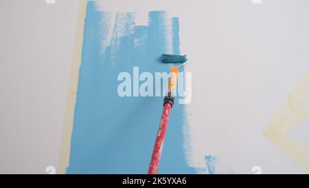 Decoratore pittura pareti in colore azzurro con rullo Foto Stock