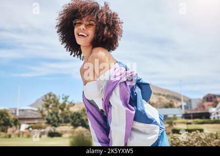 Ritratto di giovane trendy bella donna mista gara con un afrofrosorridente e in posa da solo all'esterno. Donna ispanica che indossa occhiali da sole e si sente felice Foto Stock