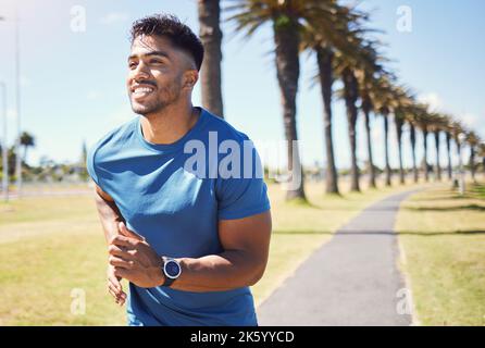 Indossa uno smartwatch per tenere traccia dei suoi progressi mentre corre all'aperto. Uomo atletico in un parco. Uomo sorridente che si esercita all'aperto. Misto Foto Stock